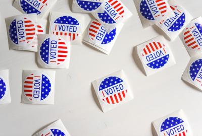 White table with 14 round "I voted" stickers scattered across decorated like the American Flag