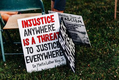 3 Protest signs placed on the ground for including a famous quote from Dr. Martin Luther King Jr., "Injustice anywhere is a threat to justice everywhere".