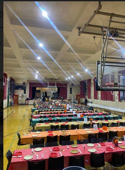 Tables set up in gymnasium with fall colors for Thanksgiving Potluck before students arrive